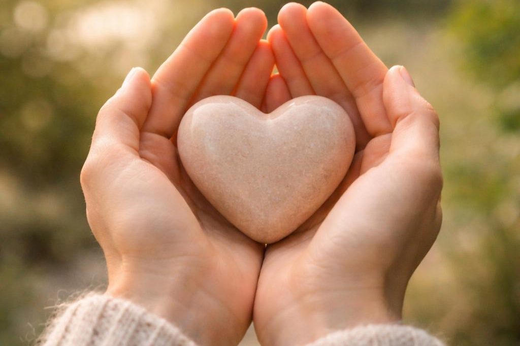 Werkboeken Twee handen houden een roze edelsteen hart vast met groene achtergrond