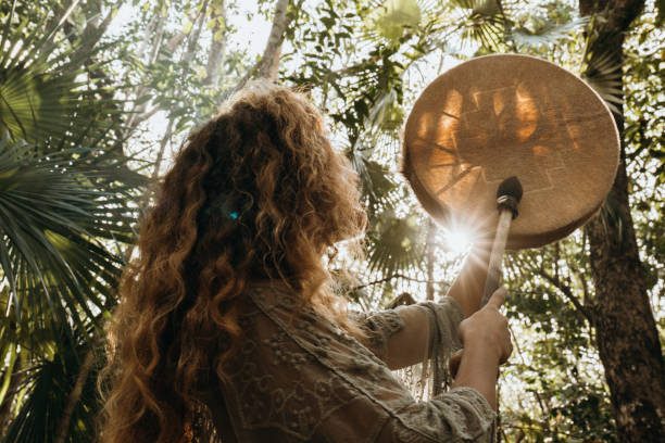 Sjamanisme Een vrouw staat in het bos en heeft een sjamanic drum vast
